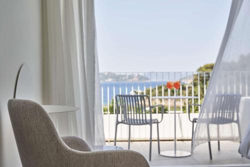 a room with a balcony with chairs and a table at Radisson Resort Plaza Skiathos in Kanapitsa