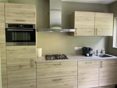 a kitchen with wooden cabinets and a stove at Comfortabel tot rust komen in het Veluwse bos in Otterlo