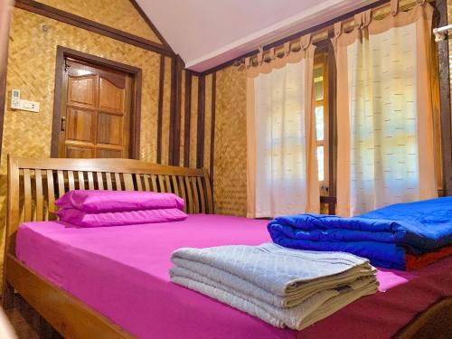 two beds in a room with pink and blue sheets at Seamthong Resort เสียมทองรีสอร์ท in Ban Siam