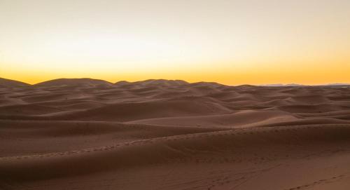 a desert with a sunset in the background at Palais Du Desert Hotel & Spa in Erfoud
