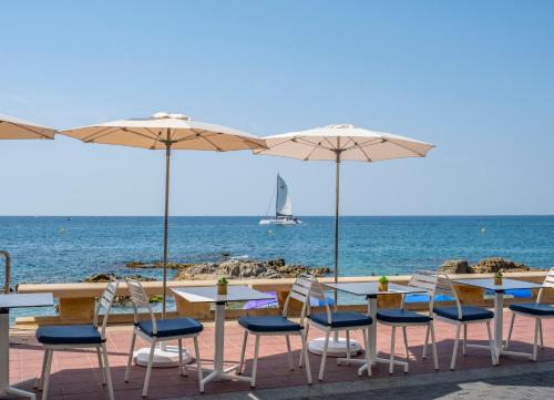 a table and chairs with umbrellas on the beach at Hotel Rosamar Maxim 4*- Adults Only in Lloret de Mar