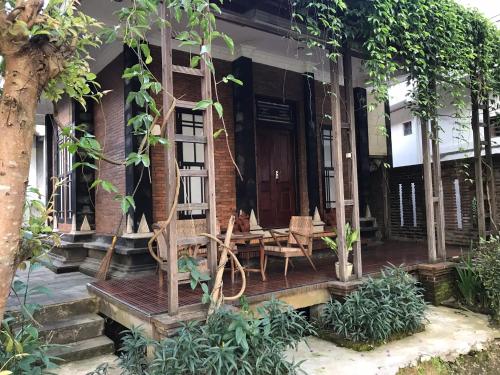 a house with a wooden porch with a table and chairs at Lotus 2 Guest House in Borobudur