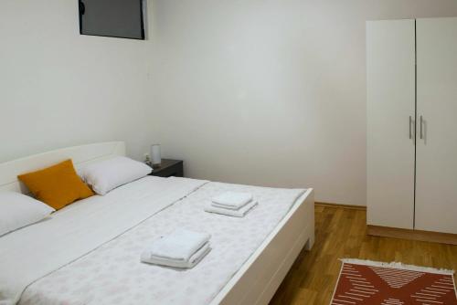 a bedroom with a large white bed with two towels on it at Apartmani Pijemont in Višegrad