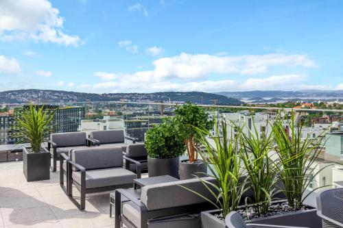 a patio with chairs and plants on a roof at Radisson RED Oslo Økern in Oslo
