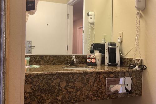 a bathroom with a sink, mirror, and soap dispenser at Baymont Inn & Suites by Wyndham Holbrook in Holbrook