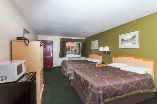 a hotel room with two beds and a tv at Super 8 by Wyndham Visalia in Visalia