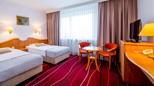 ワルシャワにあるHotel Felixのベッド2台、テーブルと椅子が備わるホテルルームです。