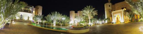 a courtyard with palm trees and a building at night at Palais Du Desert Hotel & Spa in Erfoud