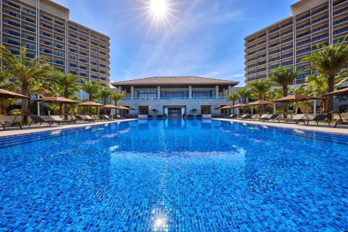 a large swimming pool with chairs and a building at Ryukyu Hotel & Resort Nashiro Beach in Itoman