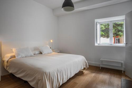 a white bedroom with a large bed with a window at Albor Suites in Santa Brígida