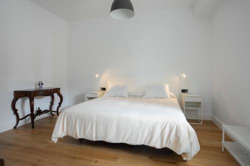 a bedroom with a white bed and a wooden floor at Albor Suites in Santa Brígida