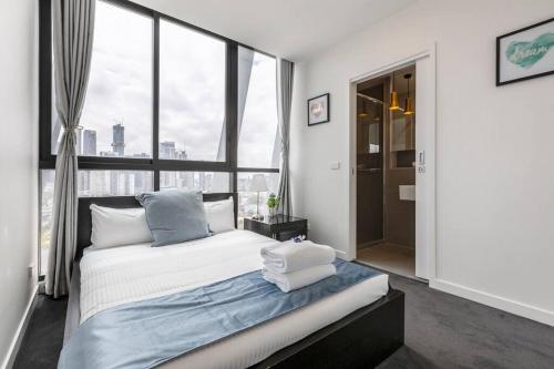 a bedroom with a bed and a large window at Modern 2 Beds Apartment with Amazing City View in Melbourne