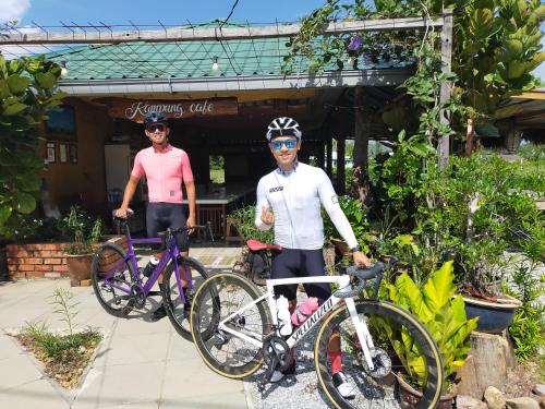 two people standing with their bikes in front of a building at Langkawi Country Lodge2 in Pantai Cenang