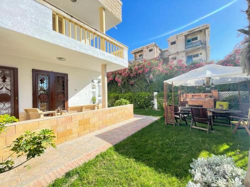 einen Hinterhof mit einem Tisch, Stühlen und einem Sonnenschirm in der Unterkunft Luxury Mamoura Alexandria Apartment in Alexandria