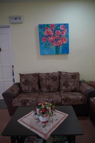 a living room with a couch and a table with flowers at Langkawi Country Lodge2 in Pantai Cenang