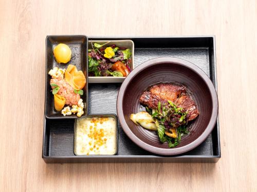 a tray with a bowl of food and a plate of food at b'mine Hotel Frankfurt Airport in Frankfurt/Main