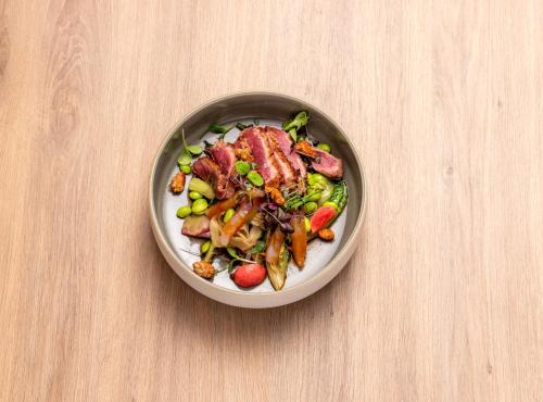 a bowl of food with meat and vegetables on a table at b'mine Hotel Frankfurt Airport in Frankfurt/Main