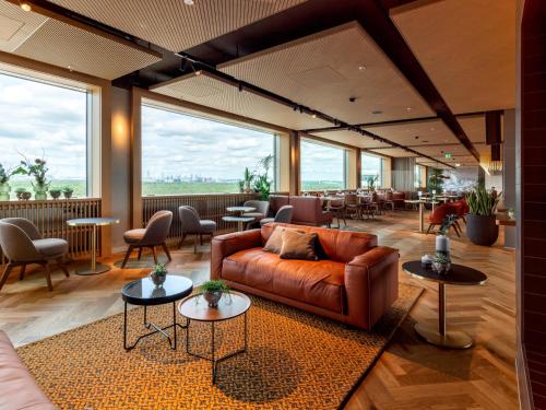 a lobby with a couch and tables and chairs at b'mine Hotel Frankfurt Airport in Frankfurt/Main