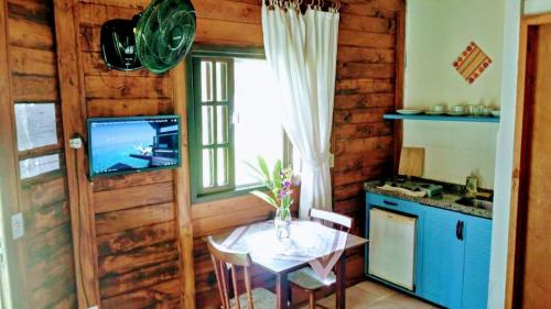 uma cozinha com uma mesa e uma televisão numa cabina em Chacara Lucinda - chales na Serra da Graciosa em Morretes
