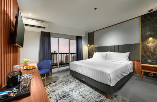 a hotel room with a bed and a desk and a television at Aston Inn Jemursari in Surabaya