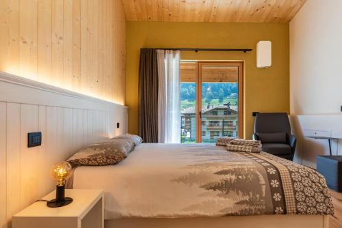 a bedroom with a bed and a chair and a window at Ciasa Fatati in Pinzolo