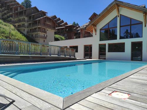 una piscina di fronte a una casa di Apt 2 chambres en duplex Chalet des Rennes Vars 2000m Piscine intérieure et extérieure a Vars
