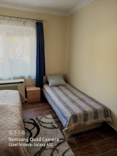 a small bedroom with a bed and a window at Írisz Apartman in Mezőkövesd