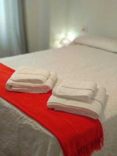 due asciugamani piegati su un letto con una coperta rossa di Oviedo Centro a Oviedo