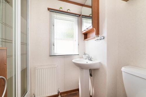 a white bathroom with a sink and a window at Dog Friendly Lovely Caravan by Beach Prestatyn N Wales 6 Berth Read full Host details before booking Mon in to Fri out Fri in to Mon out Mon to Mon Fri to Fri ONLY in Prestatyn