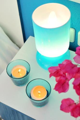 three candles in small bowls on a table with flowers at Aiolis Studios in Porto Koufo