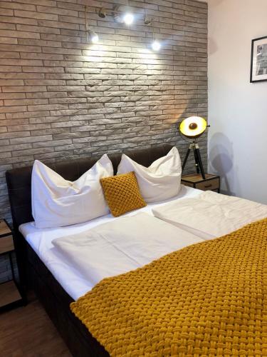 a large bed with white pillows and a brick wall at Penzión u Vinára in Veľký Krtíš