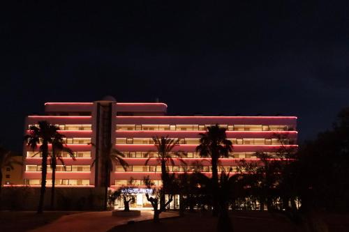 einem beleuchteten Gebäude mit Palmen davor in der Unterkunft El Hotel Pacha in Ibiza-Stadt