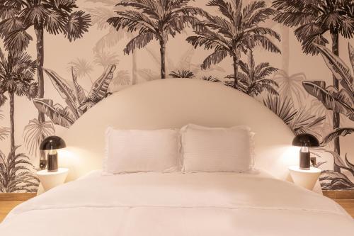 um quarto com uma cama branca e papel de parede com palmeiras em Desert Living Luxury Condo - Jumeirah Living Marina Gate em Dubai