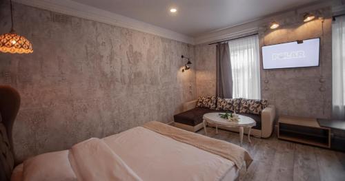a bedroom with a bed and a table and a tv at Biplan Hotel in Daugavpils