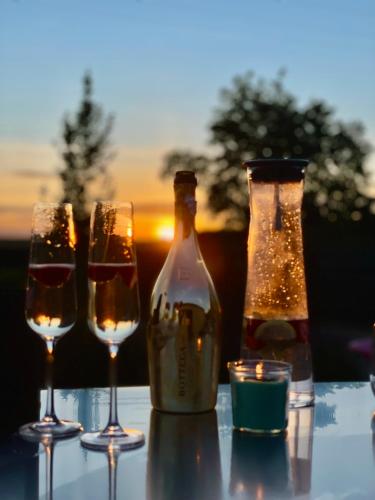 three wine glasses and a bottle on a table with the sunset at M.F. in Znojmo