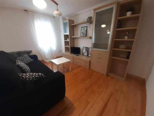 - un salon avec un canapé noir et du parquet dans l'établissement Apartamento Chantría Lucía, à Teruel