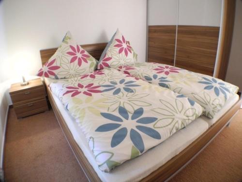 a bed with a flower patterned sheets and pillows at Möwennest 11 - Großenbrode in Großenbrode