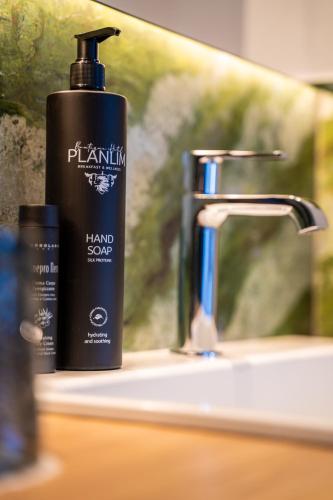 a black bottle of hand soap next to a sink at Boutique Hotel Planlim in Ortisei