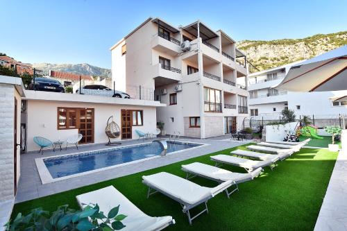 a building with a swimming pool and lounge chairs at Villa Lazy Hill in Budva