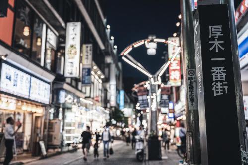 a busy city street at night with people walking down the street at Hotel Vista Atsugi in Atsugi