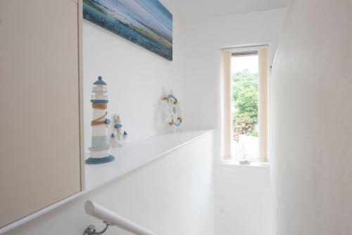 a white bathroom with a mirror and a window at Kerensa in Portreath