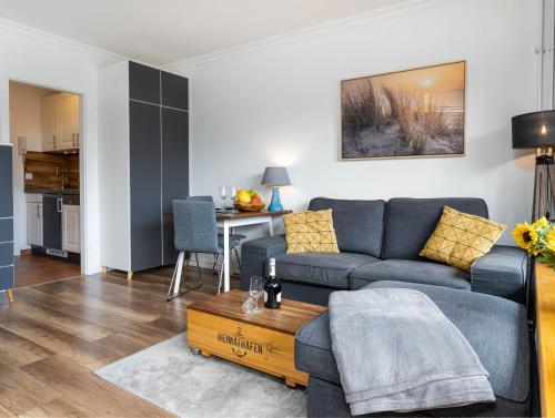 ein Wohnzimmer mit einem blauen Sofa und einem Tisch in der Unterkunft Ferienwohnung Abendsonne in Wenningstedt-Braderup
