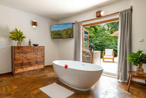 a bathroom with a large white tub and a sliding glass door at White Paradise Zanzibar in Pongwe