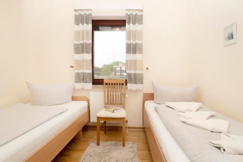 twee bedden in een kamer met een stoel en een raam bij Grömitz Center I Wohnung 313 in Grömitz