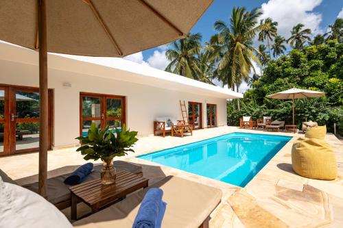 a villa with a swimming pool and a house at White Paradise Zanzibar in Pongwe