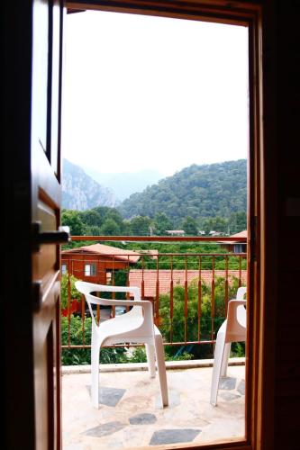 a view of a balcony with two white chairs at Rosemary Pansiyon in Cıralı