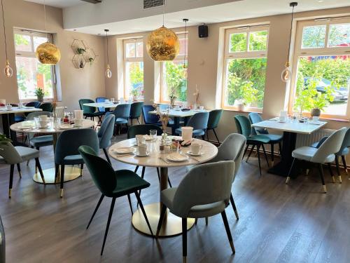 a dining room with tables and chairs and windows at Hotel Xenia Flensburg in Flensburg