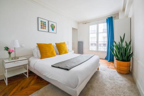 ein weißes Schlafzimmer mit einem großen Bett und gelben Kissen in der Unterkunft Appartements Bergère in Paris