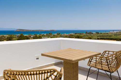 a wooden table and chairs on a balcony with the ocean at Golden Bay luxury villas and suites in Chrissi Akti