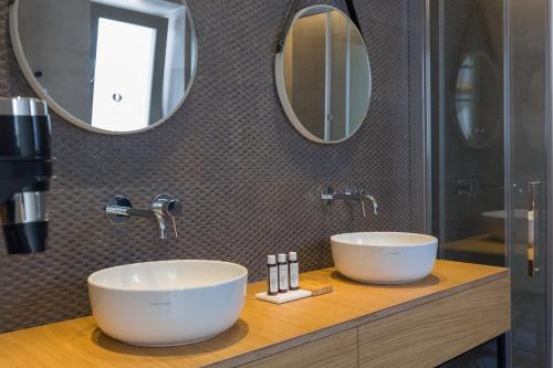 a bathroom with two sinks and two mirrors at Golden Bay luxury villas and suites in Chrissi Akti
